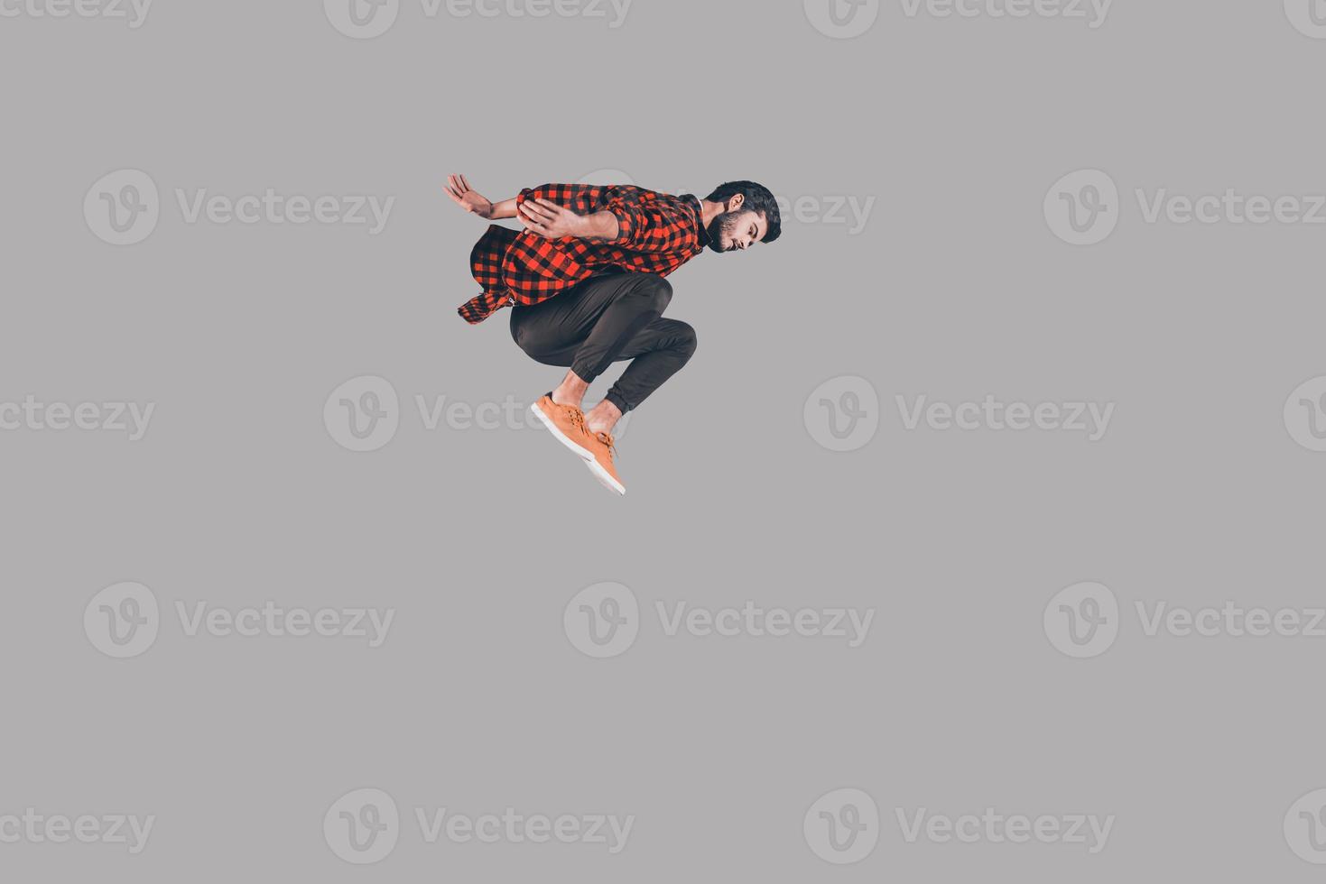 In motion. Mid-air shot of handsome young man jumping and gesturing against background photo