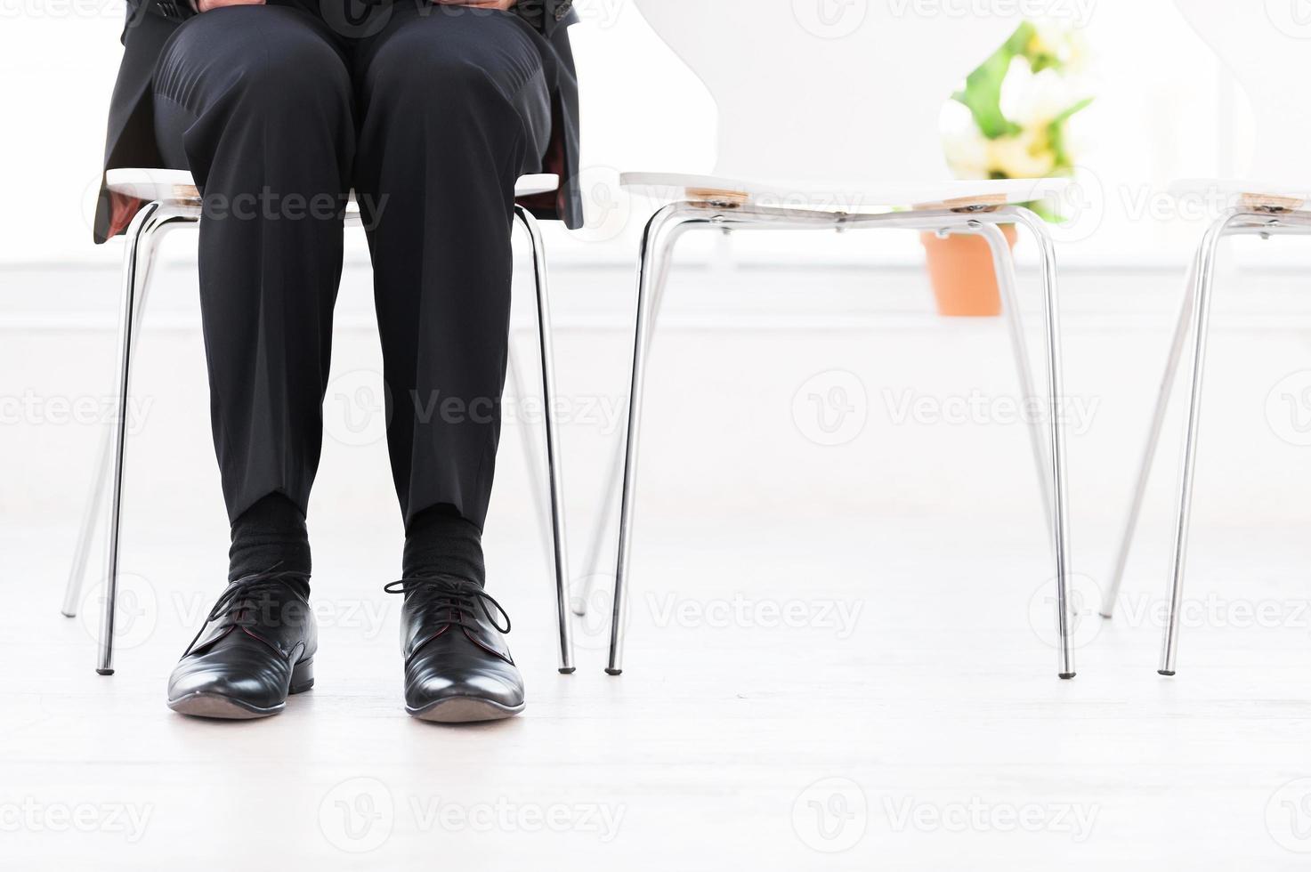 Waiting for interview. Cropped image of man in formalwear sitting at the chair with other chairs standing in a row photo