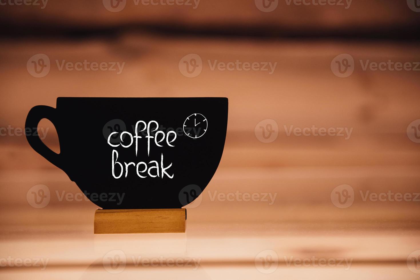 Coffee break. Cup shaped blackboard with hand writing text at wood background photo