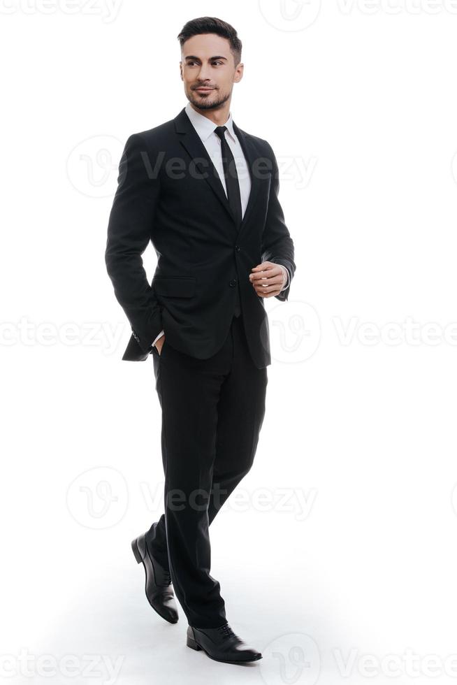 Perfect style. Full length of handsome young man in full suit holding one hand in pocket and looking away while standing against white background photo