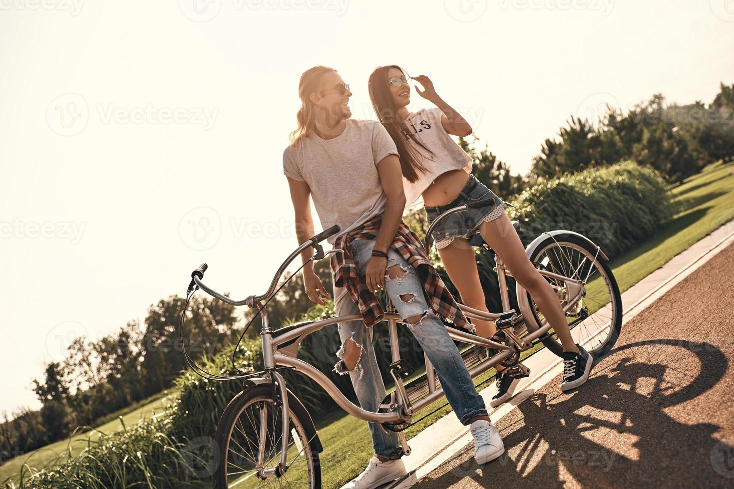 siempre juntos. hermosa pareja joven en ropa casual en bicicleta juntos mientras pasan tiempo sin preocupaciones al aire libre foto