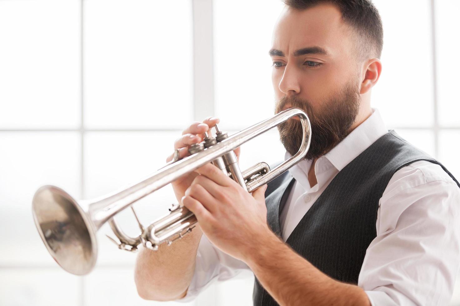 improvisando con su trompeta. guapos jóvenes barbudos tocando la trompeta foto