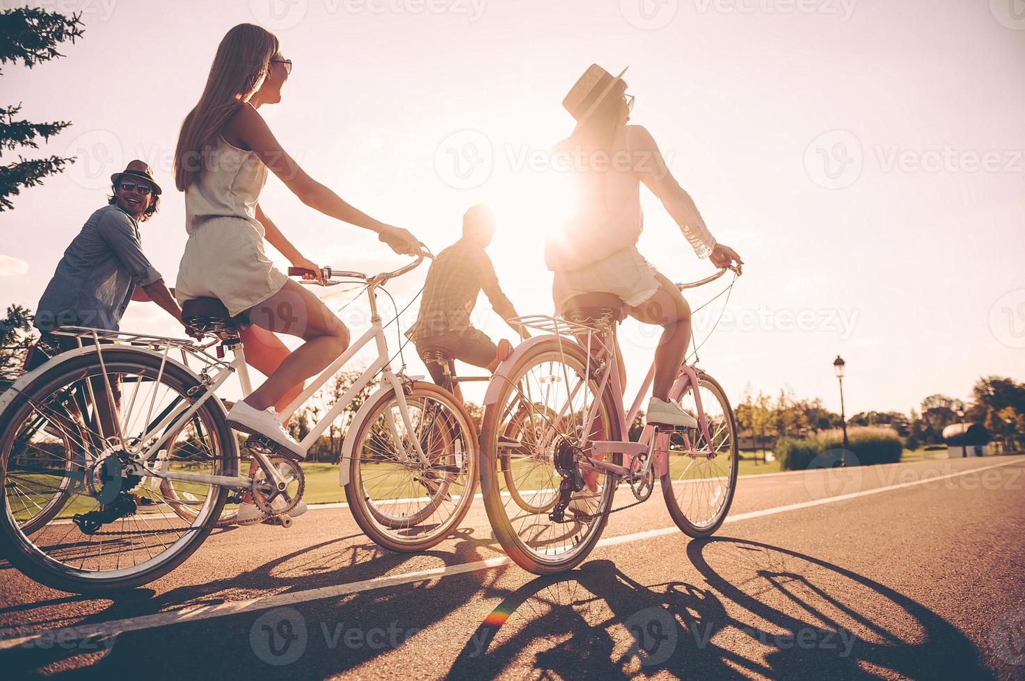 Freedom is in their veins. Low angle view of young people riding bicycles along a road and looking happy photo