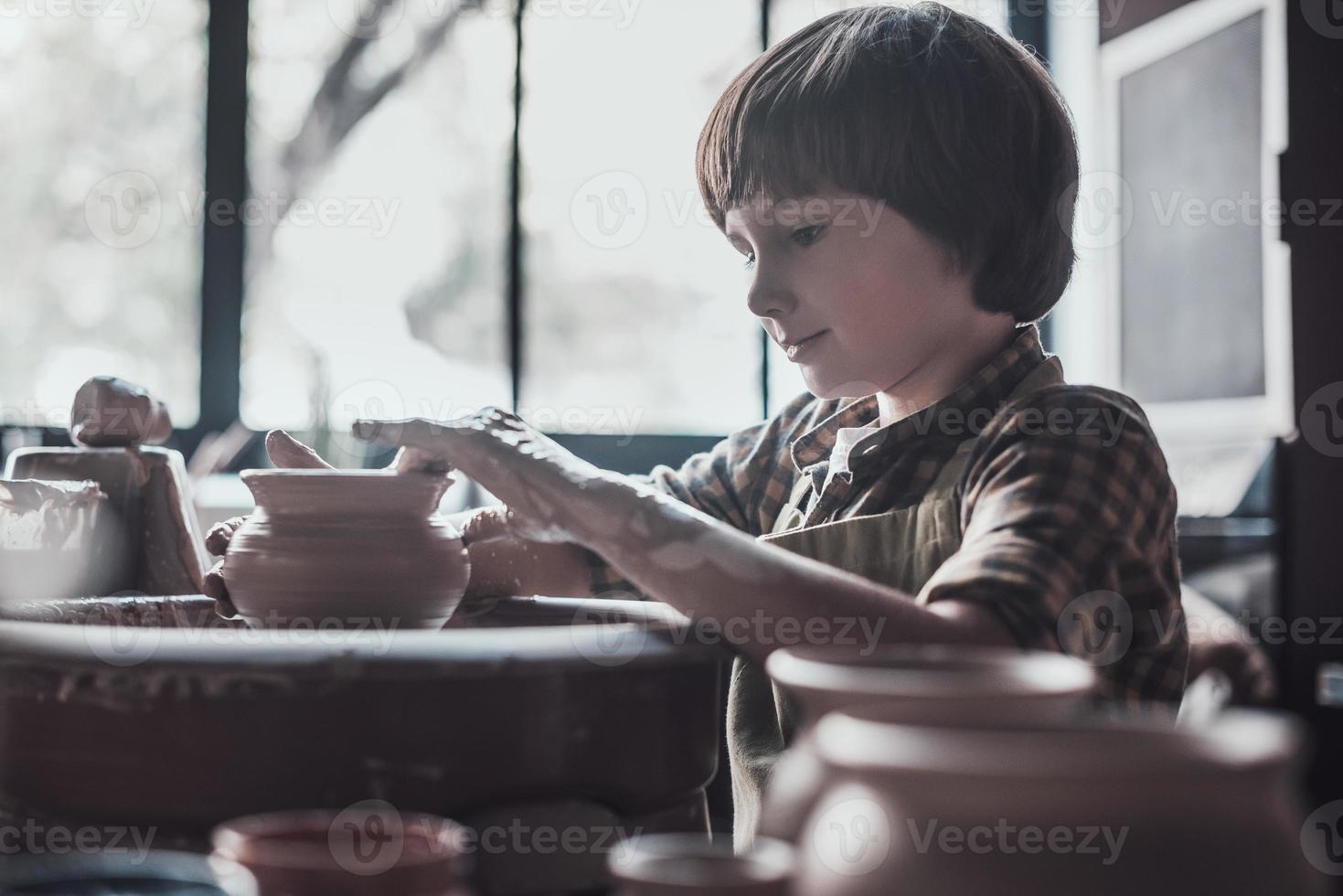 le encanta la alfarería. niño confiado haciendo vasija de cerámica en la clase de cerámica foto