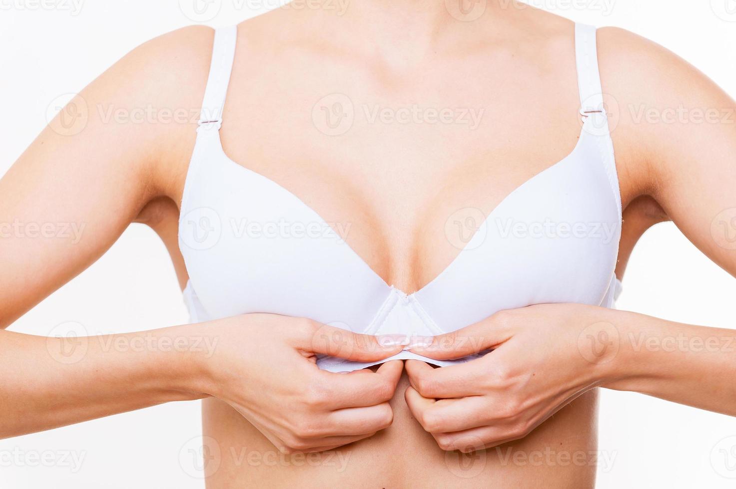 Dressing up bra. Close-up of woman dressing up white bra while standing isolated on white photo