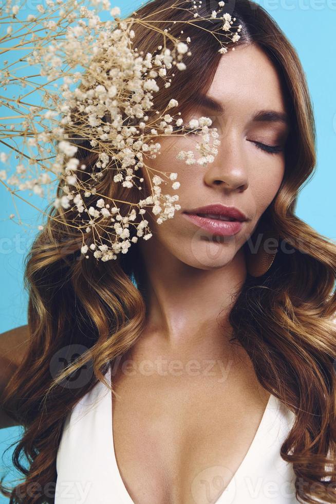 retrato de una hermosa joven que mantiene los ojos cerrados mientras se enfrenta al fondo azul foto