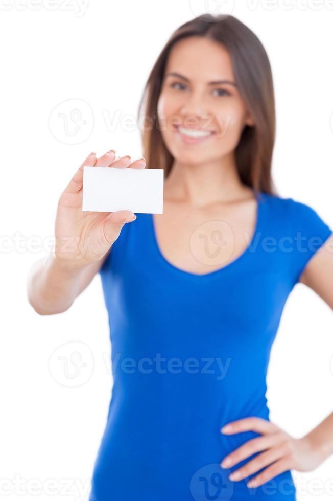 Copy space on her hand. Attractive young smiling woman showing a business card and smiling while standing isolated on white photo