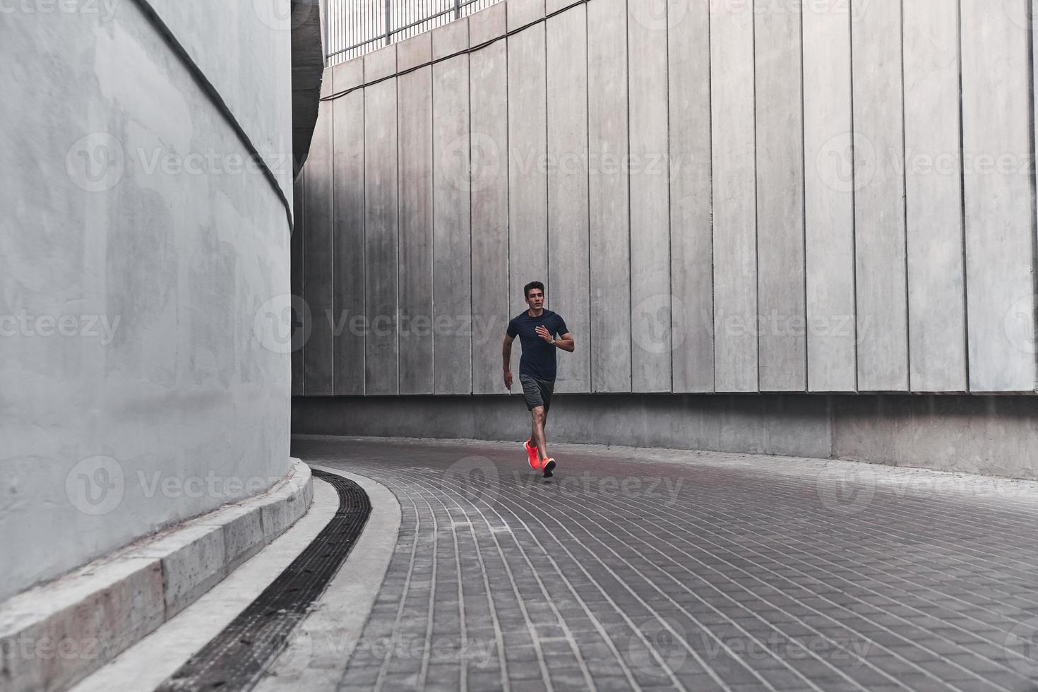 Stronger and faster. Full length of young man in sports clothing running while exercising outside photo