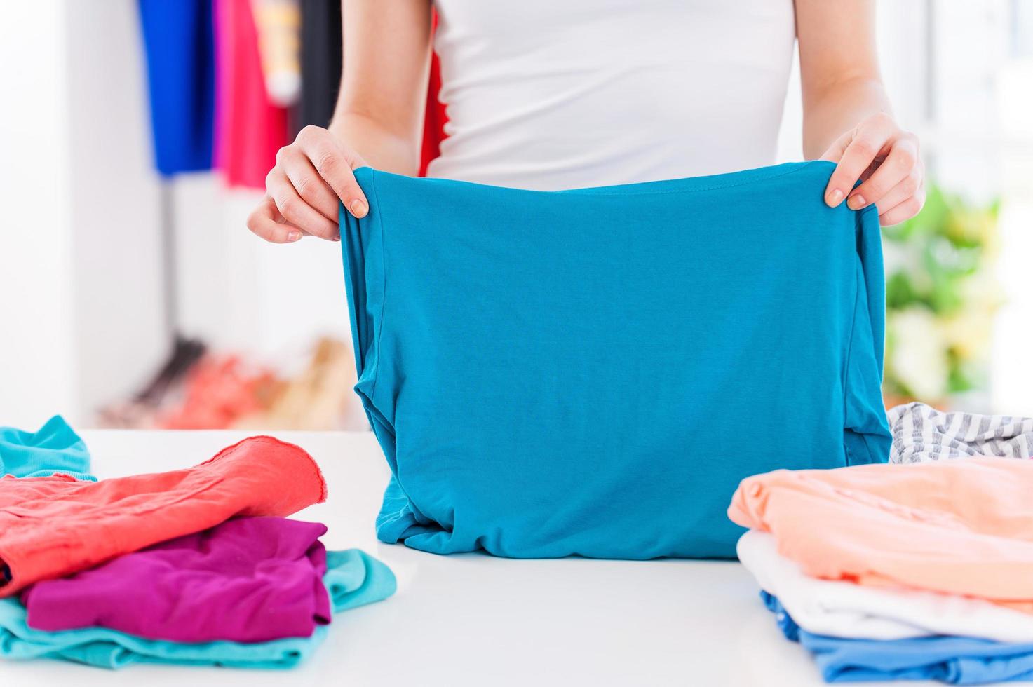 Folding clothes. Cropped image of woman folding clothes on the table photo