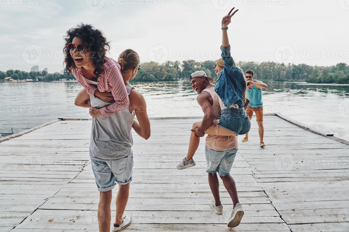 Best way to spend the weekend. Beautiful young couples spending carefree time while standing on the pier photo