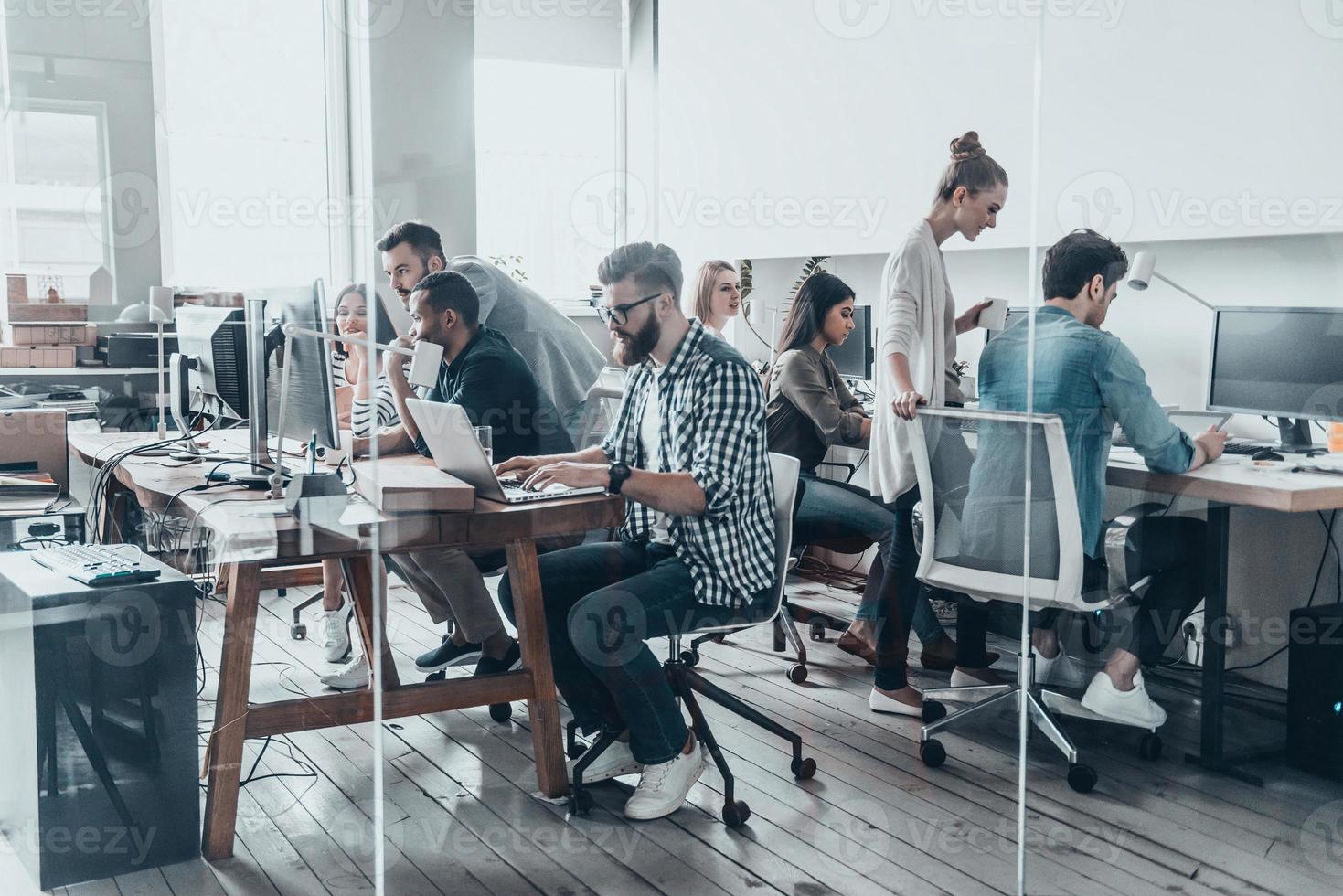 equipo de negocios creativos. grupo de jóvenes empresarios que trabajan y se comunican juntos mientras están sentados en sus lugares de trabajo en el cargo foto