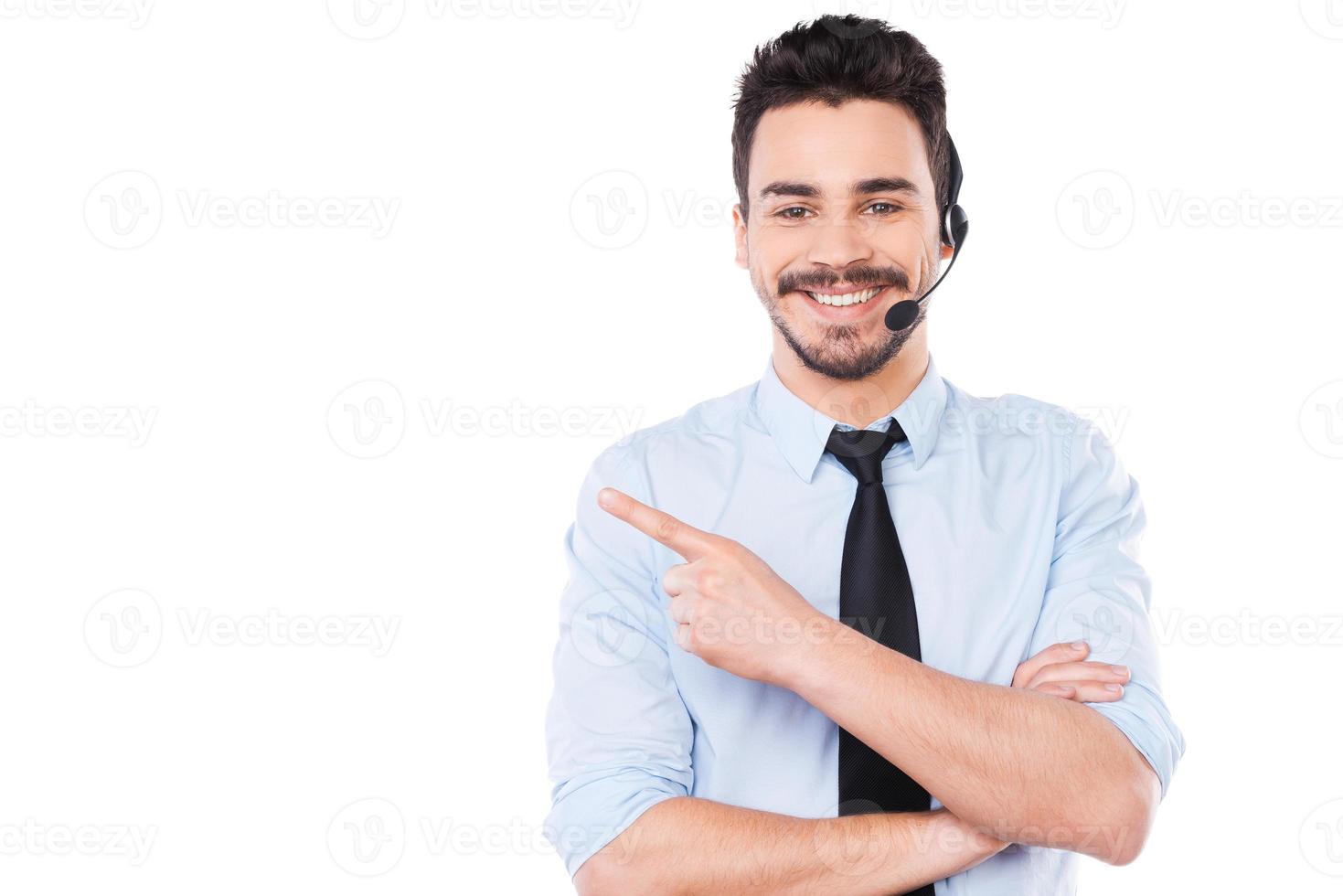 Advertising your product. Handsome young male operator pointing away and smiling while standing against white background photo