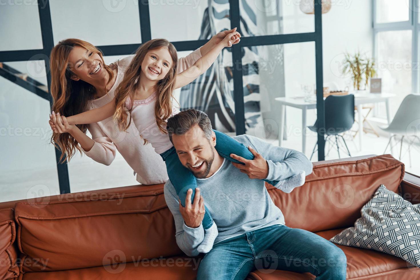 Cheerful young family bonding together while sitting on sofa at home photo
