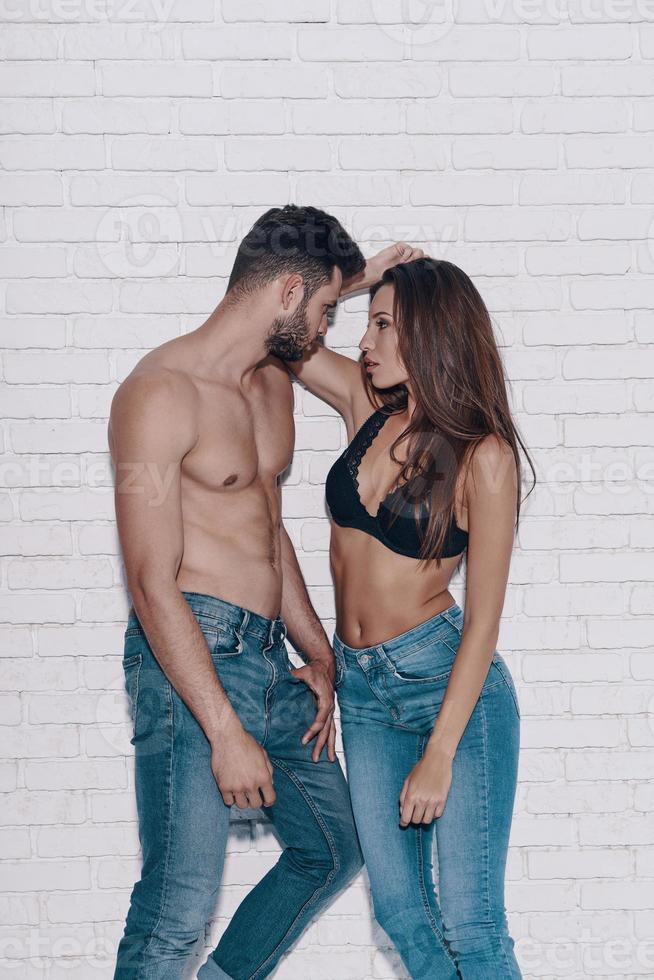 Endless love. Beautiful young couple looking at each other while standing against brick wall photo