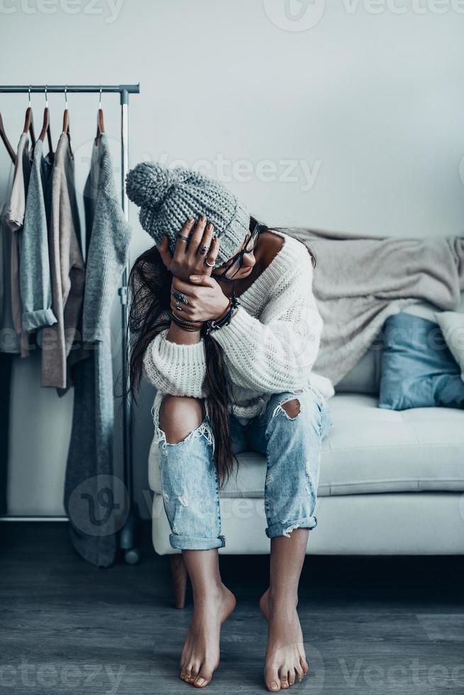 frente a una elección difícil. una joven pensativa con ropa informal cogida de la mano y mirando hacia otro lado cerca de su ropa colgada en los estantes foto