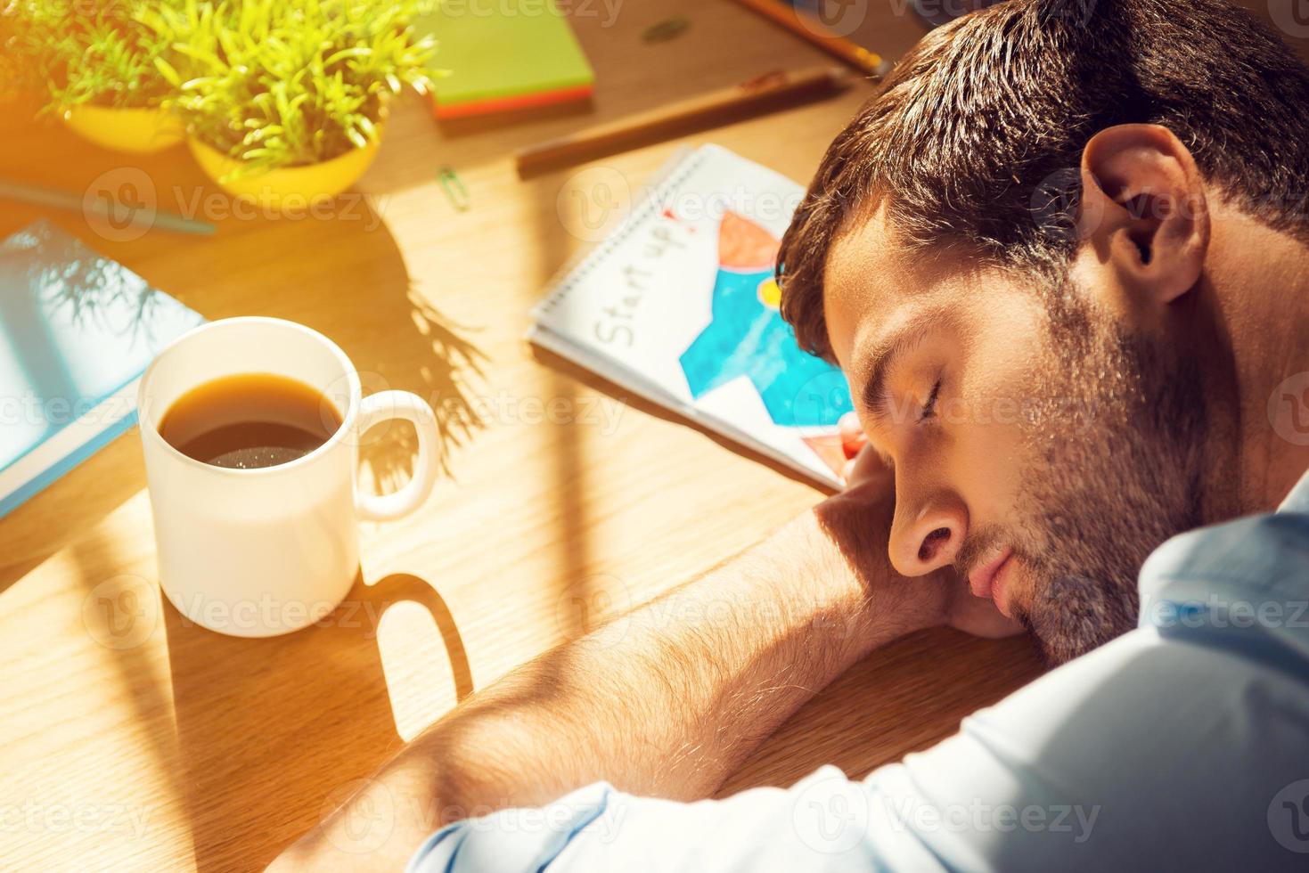Giving all his energy to work. Close-up top view of tired man sleeping while sitting at his working place photo