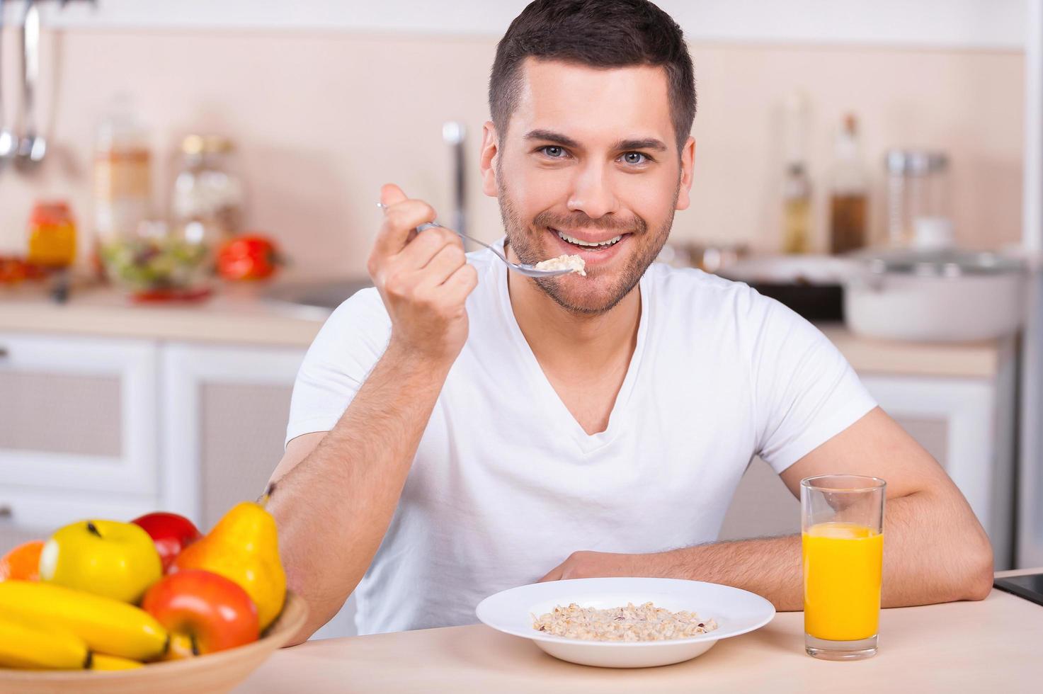 Healthy breakfast. Handsome young man having a healthy breakfast while sitting in the kitchen photo