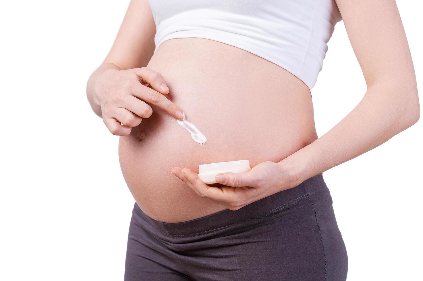 Applying moisturizer. Cropped image of pregnant woman applying moisturizer on her pregnant belly