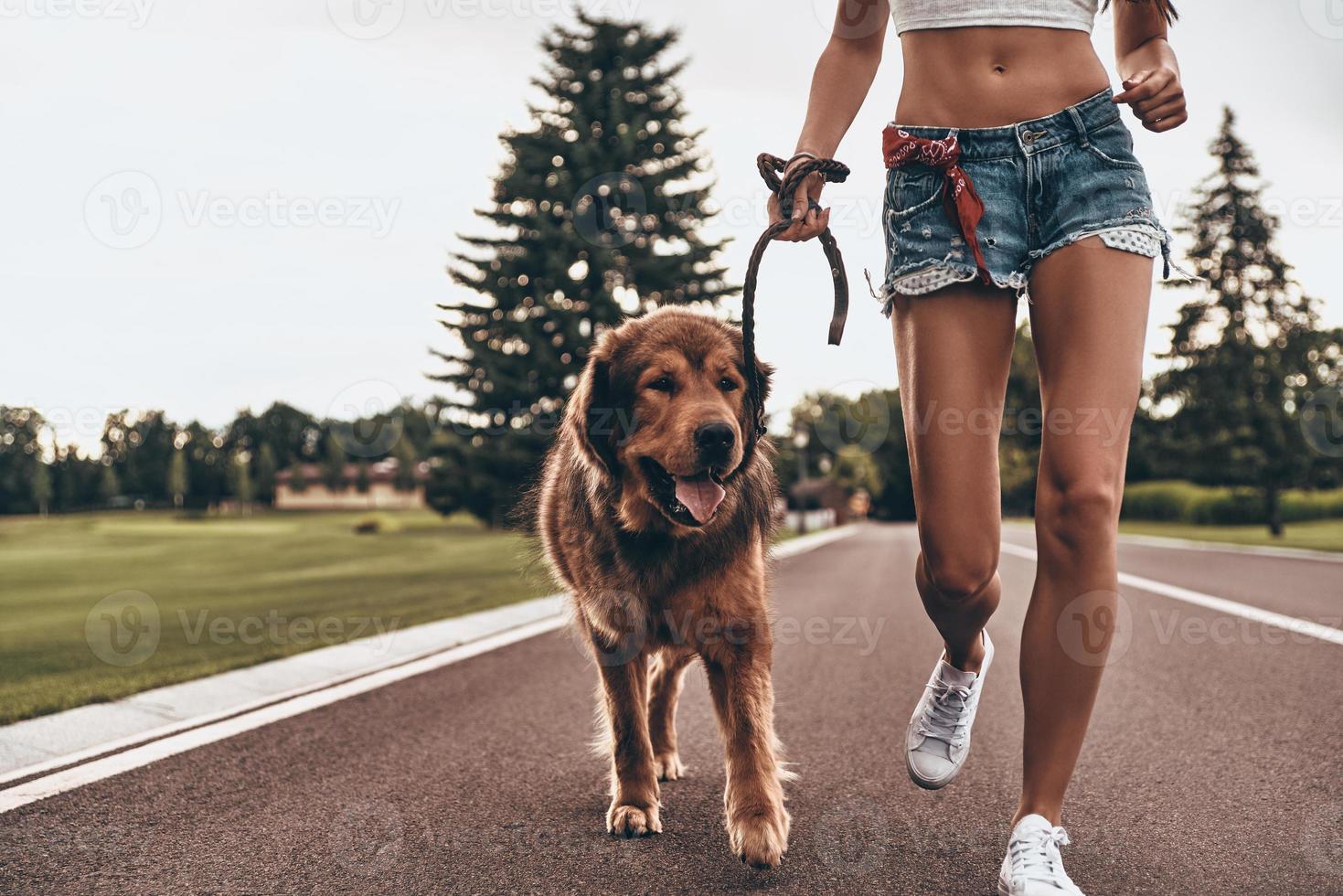 Getting some fresh air. Close-up of young woman running with her dog through the park while spending time outdoors photo