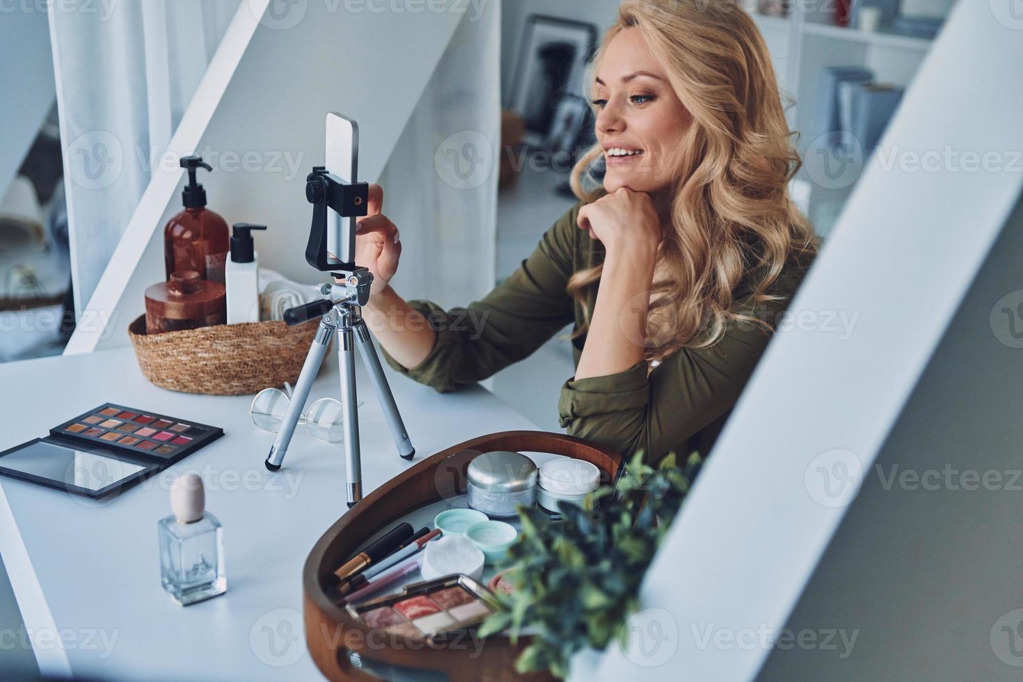 Beautiful young smiling woman vlogging about make up and beauty products photo