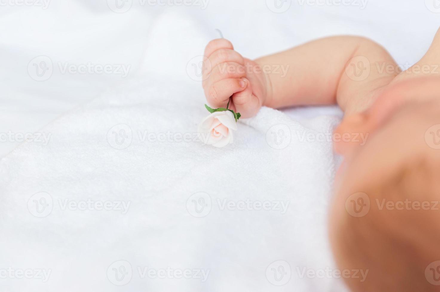 bebé con flor. vista superior del pequeño bebé acostado en la cama y mirando a la cámara foto