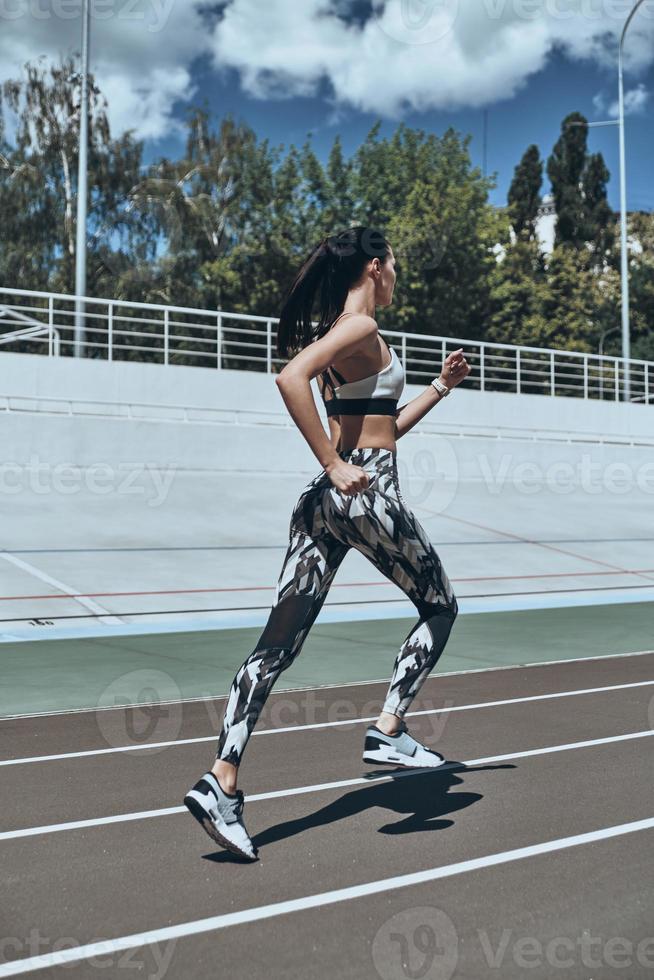 Morning workout. Full length of young woman in sports clothing jogging while exercising outdoors photo