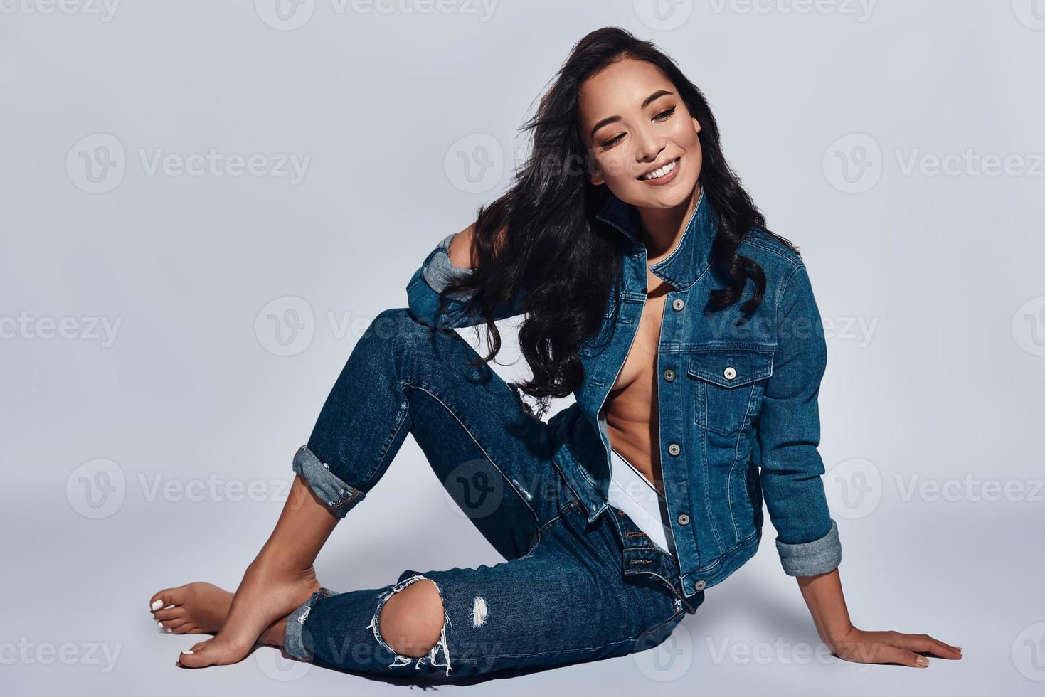 Sweet seduction. Attractive young woman smiling while sitting against grey background photo