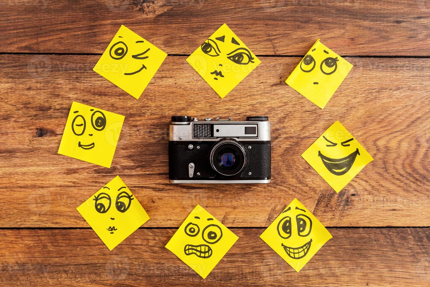 Emotional circle. Close-up of retro camera surrounding by adhesive notes with drawings on them photo