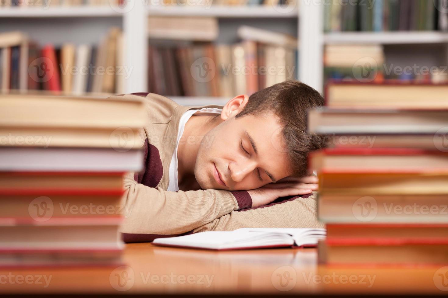 Sleeping at the library. Tired young man sleeping near the book stacks at the library photo