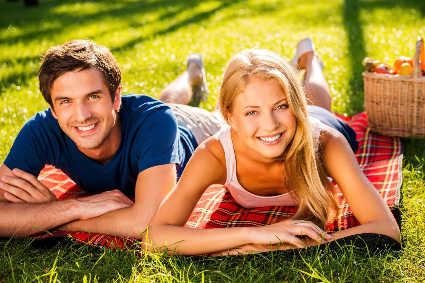 Relaxing in park together. Happy young loving couple relaxing in park together while lying on picnic blanket photo