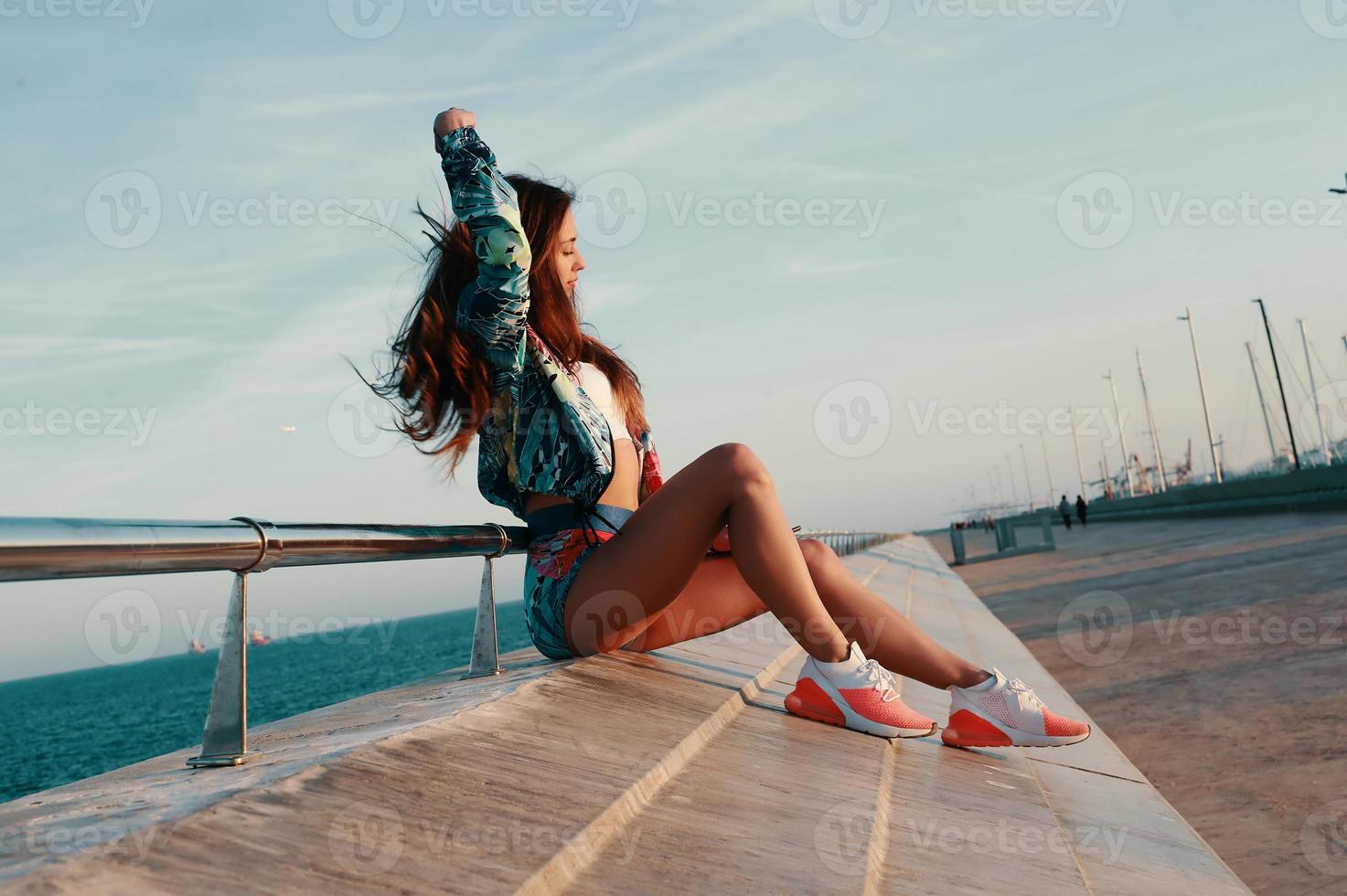 Attractive young woman relaxing while sitting near the beach outdoors photo
