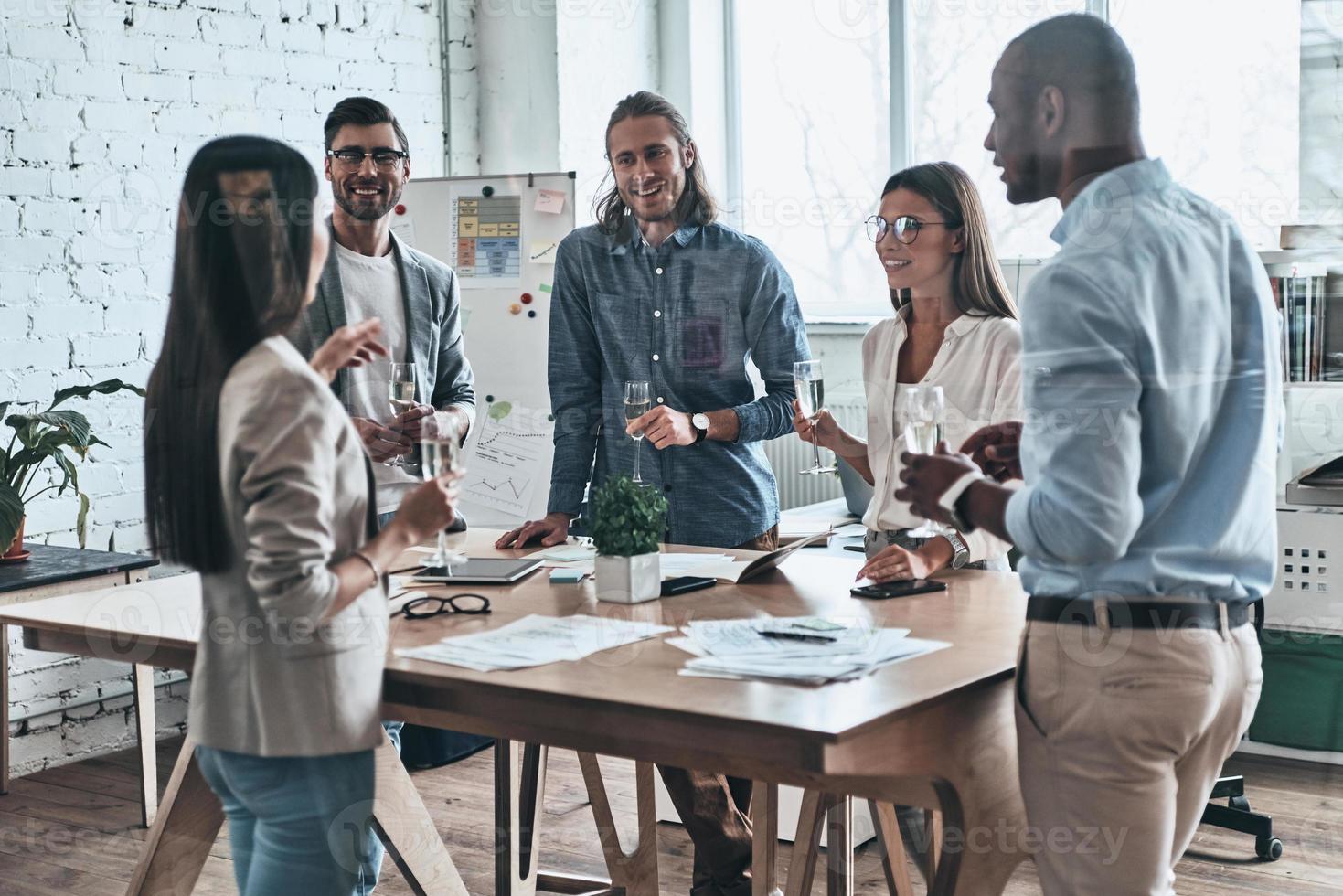 Office party. Diverse group of young business people drinking champagne and smiling while standing in the board room photo