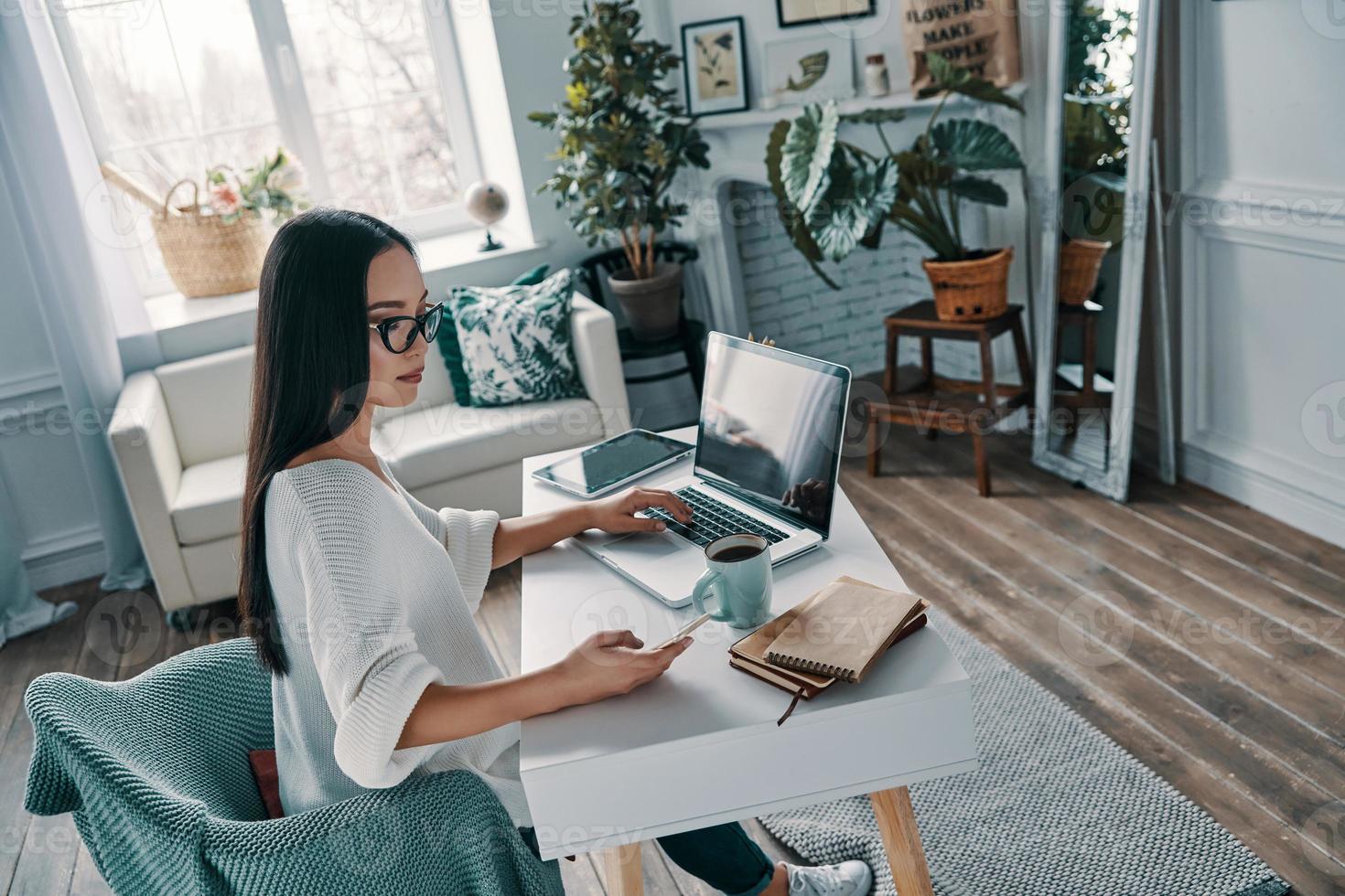 Working from home. Top view of beautiful young woman working using laptop while sitting in home office photo