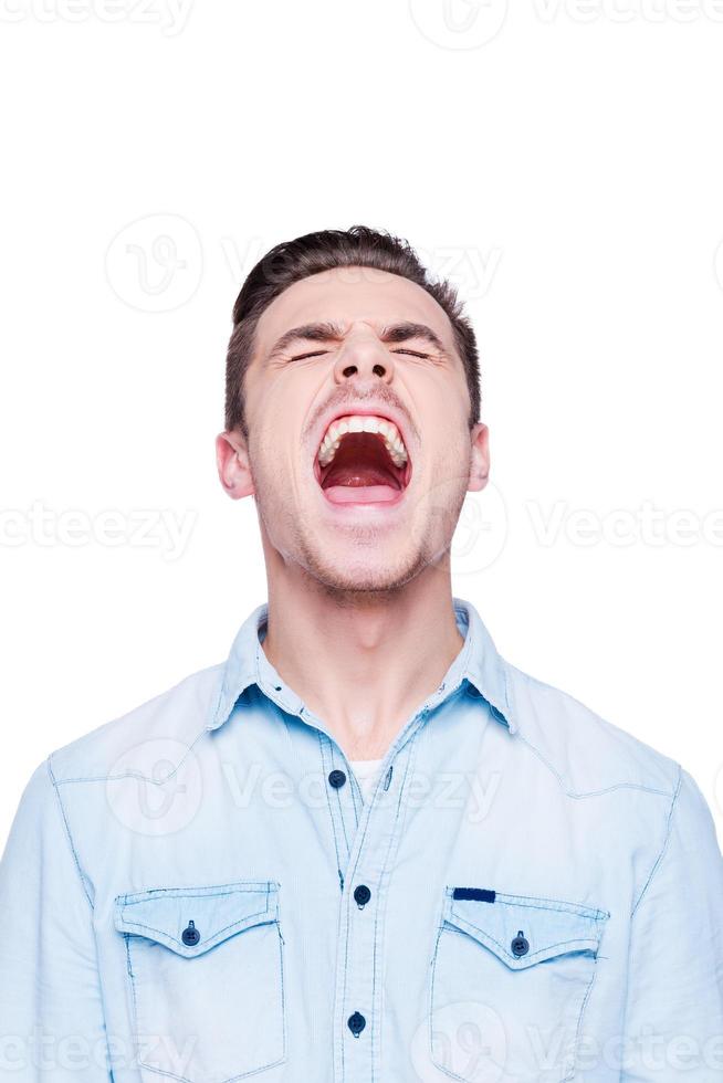 Cry of despair. Handsome young man shouting while standing against white background photo