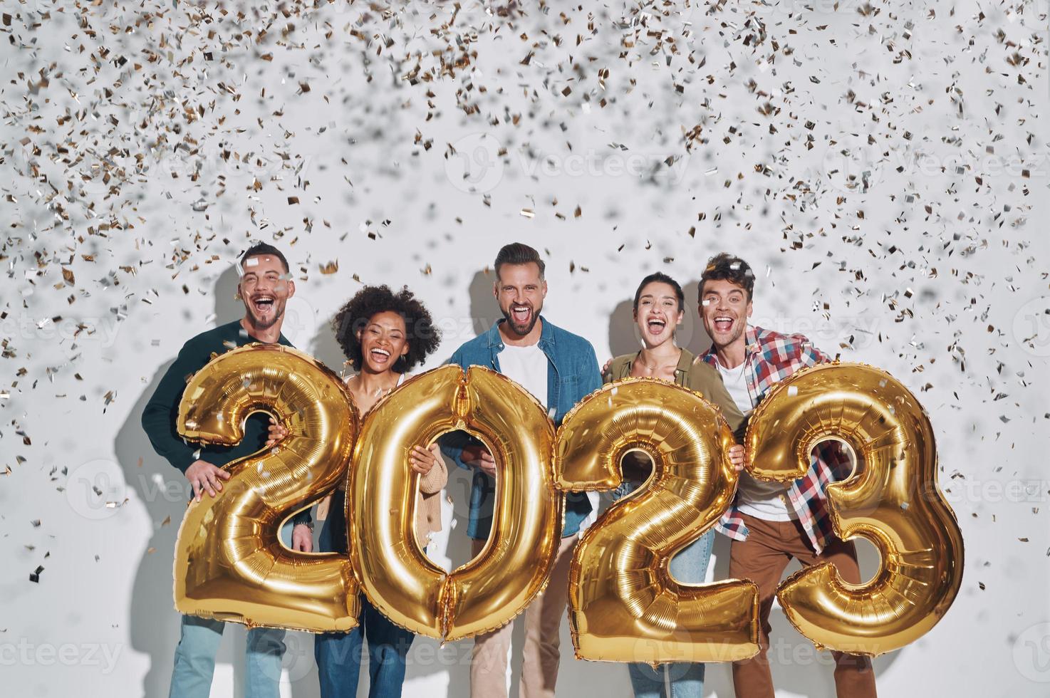 grupo de jóvenes hermosos con ropa informal que llevan números dorados y sonríen foto