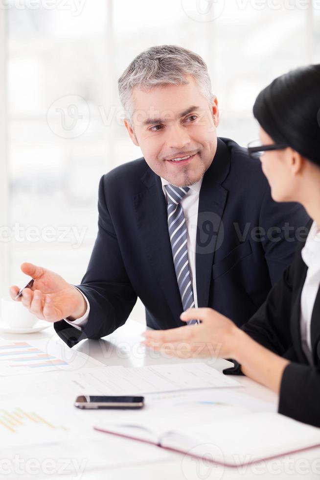 Business colleagues at work. Two cheerful business people discussing something and gesturing while sitting together at the table photo