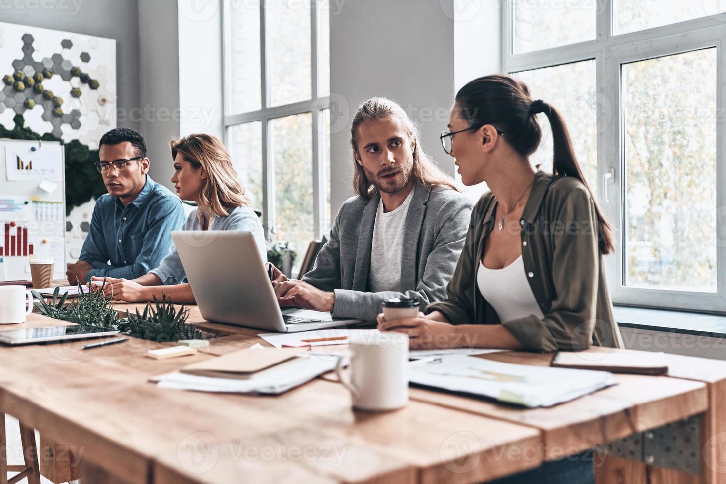 Mutual understanding. Group of young modern people in smart casual wear discussing business while working in the creative office photo
