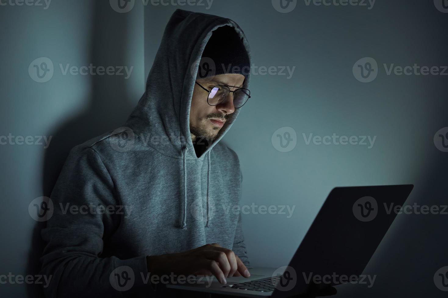 Confident young man in hooded shirt using computer while working late photo