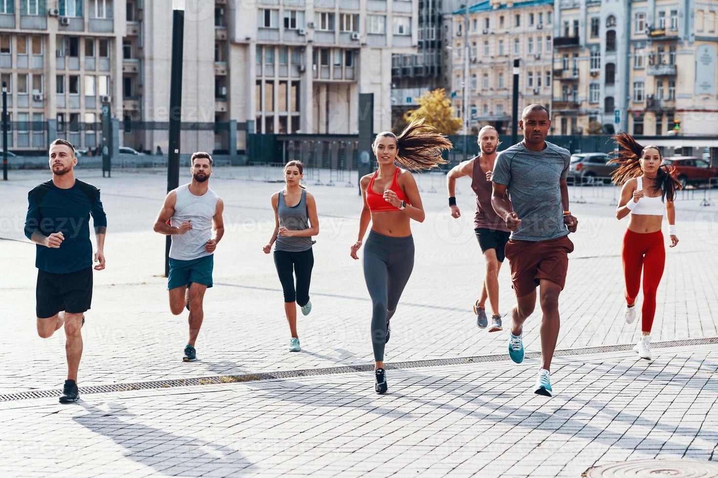 toda la longitud de la gente con ropa deportiva trotando mientras hace ejercicio en la acera al aire libre foto