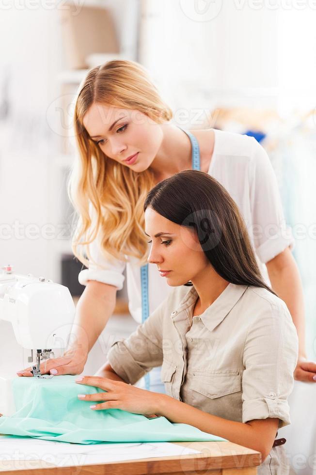 They are always ready to help each other. Two confident young women sewing together in their workshop photo