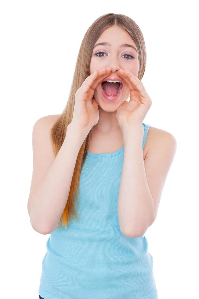 Announcing good news. Cheerful teenage girl shouting and holding hands near mouth while standing isolated on white photo