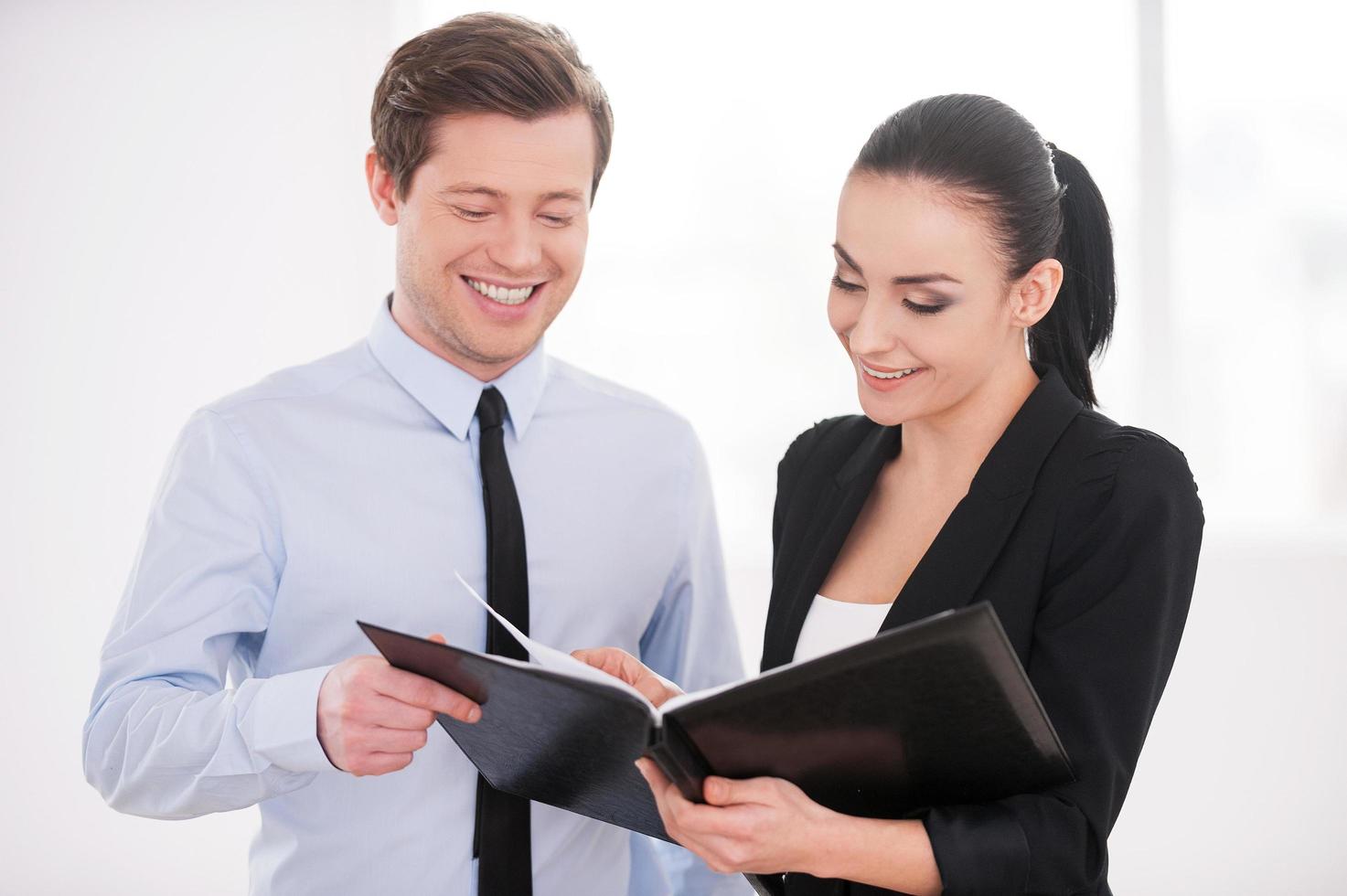 Discussing contract. Young man and woman in formalwear discussing something while holding folder with documents photo