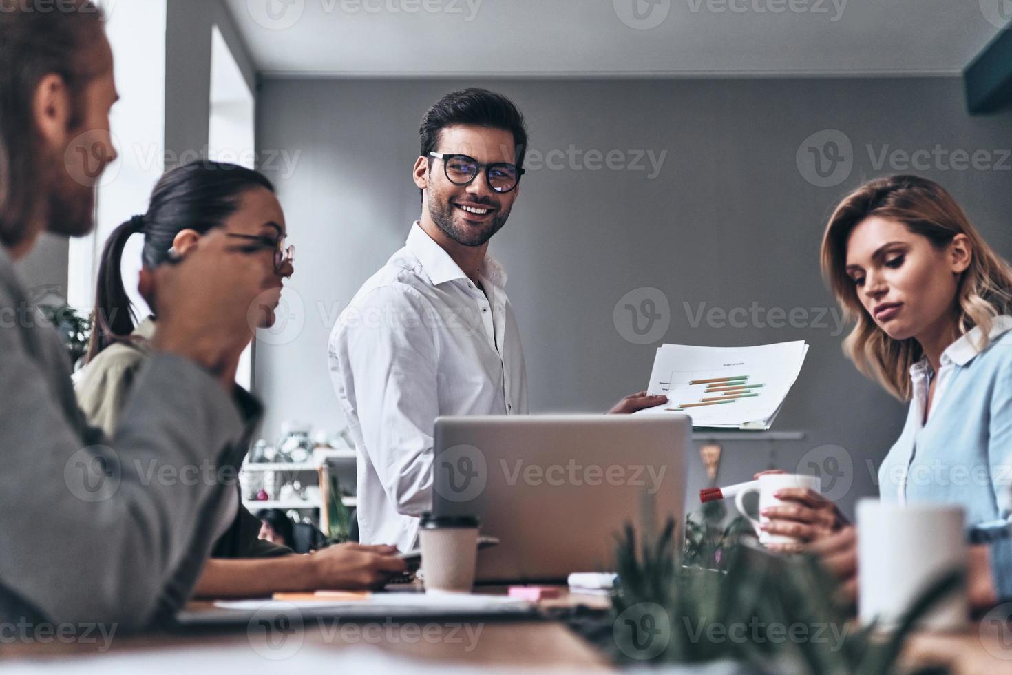 Sharing fresh ideas. Group of young modern people in smart casual wear discussing business while working in the creative office photo