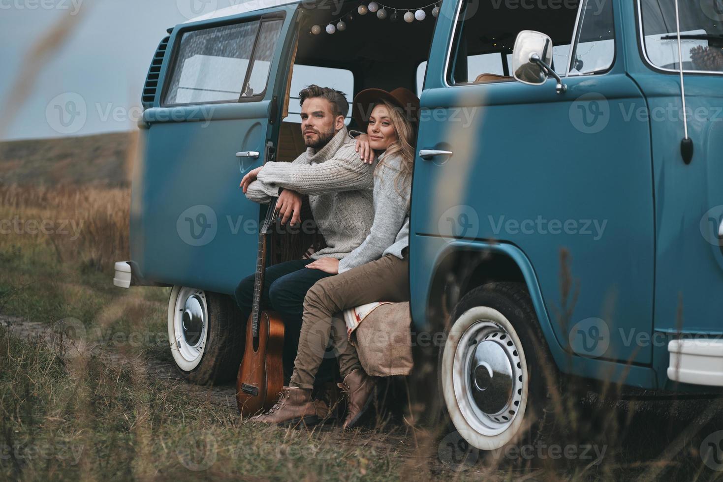 Just stopped to enjoy the view.  Beautiful young couple looking away and smiling while sitting in blue retro style mini van photo