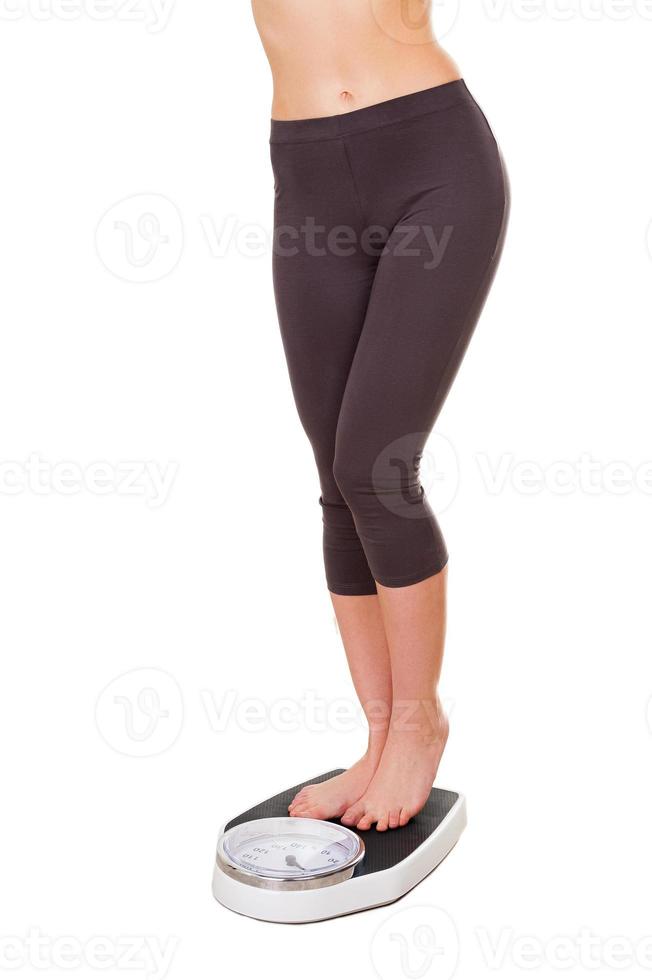 Weight control. Cropped image of young woman in sports clothing standing on weight scale photo