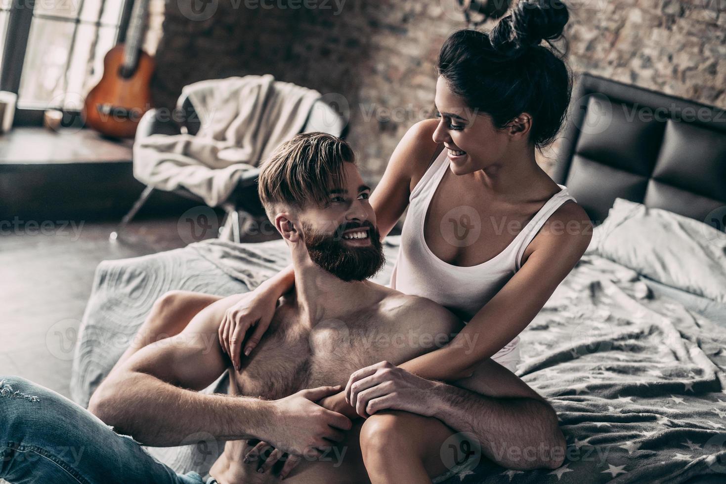 Enjoying every minute together. Attractive young people smiling and looking at each other while resting at home together photo