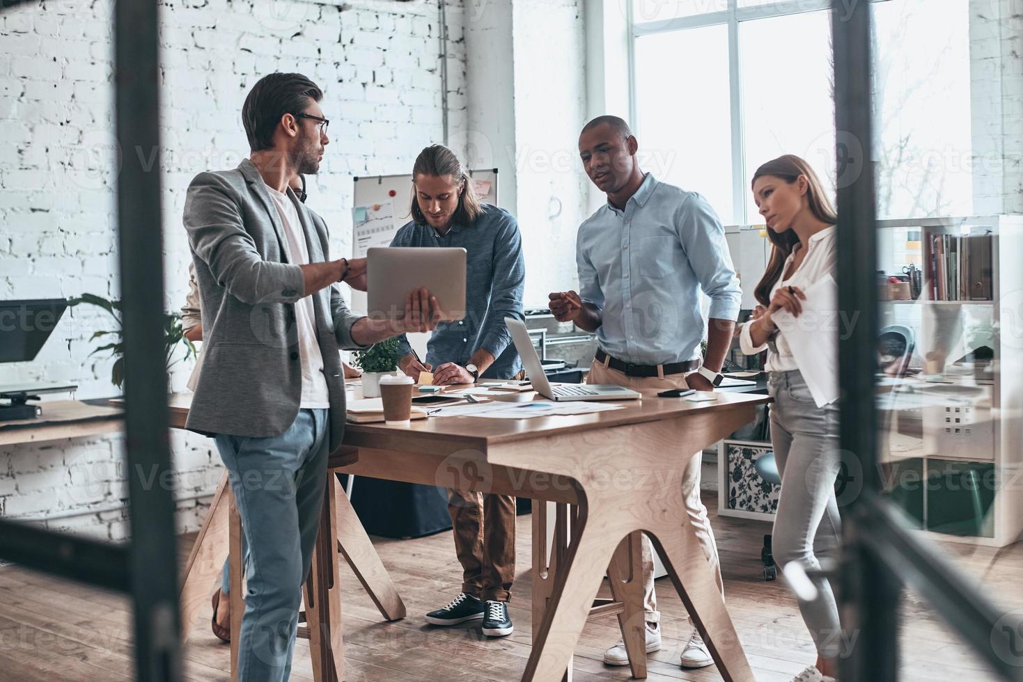 Sharing new ideas. Group of young modern people communicating together while working in the board room photo