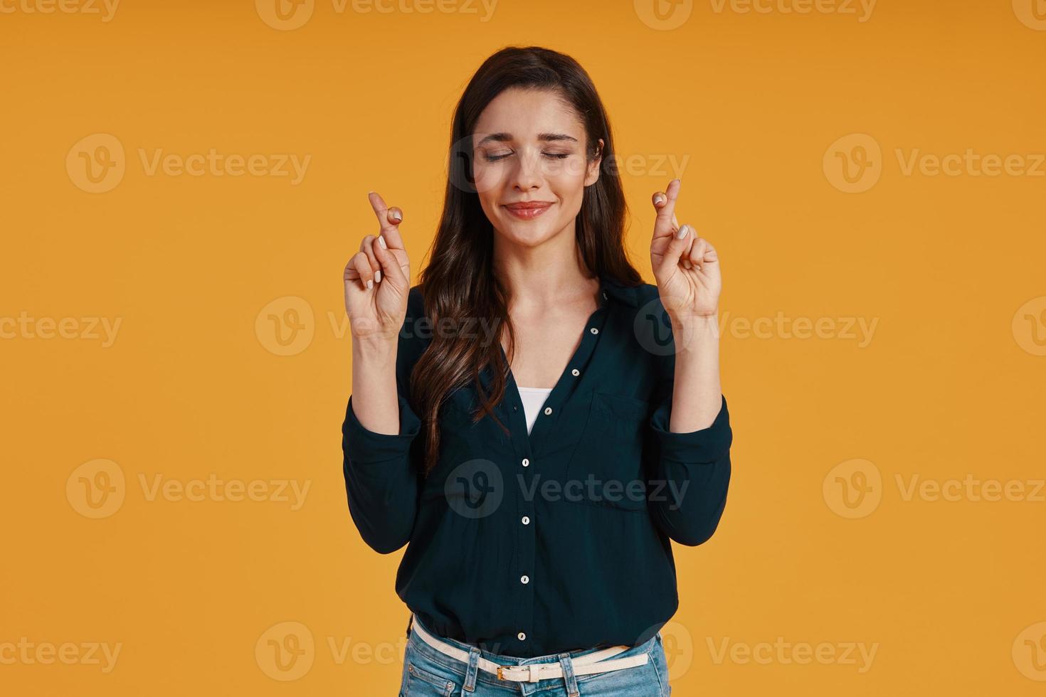 Attractive young woman in casual clothing crossbreeding fingers and smiling photo