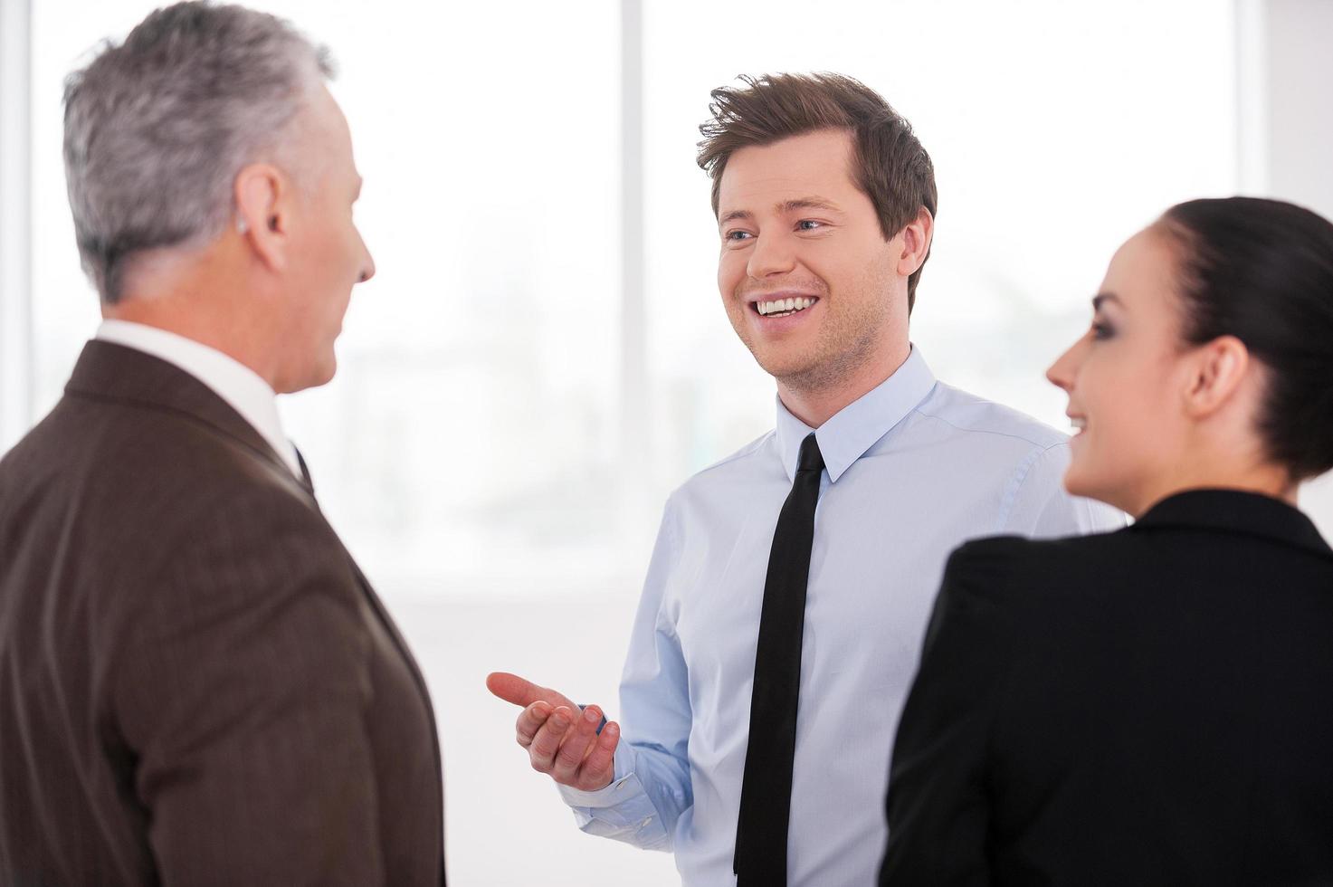 discutiendo un proyecto exitoso. tres empresarios alegres discutiendo algo mientras están cerca uno del otro foto