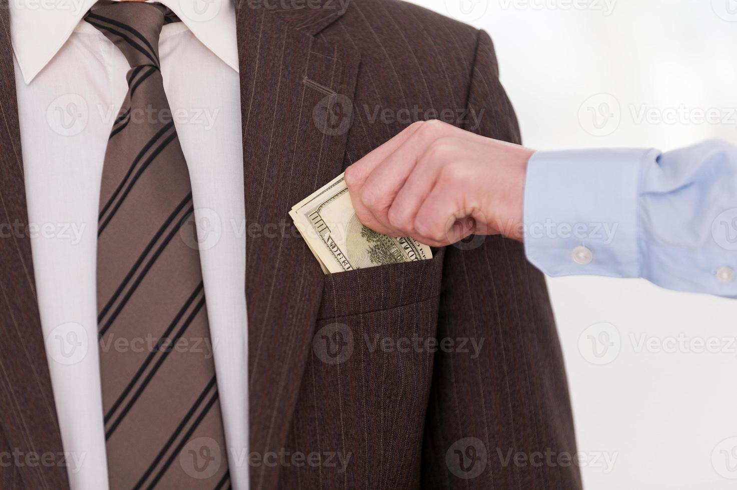 Bribing. Close-up of businessman putting money to the pocket of another man in formalwear photo
